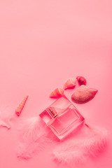 bottle of female perfume on a pink background with shells and feathers, a gentle background, a gift for a woman