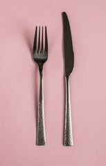 fork and knife on a pink background, tools for food