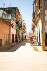 Fototapeta na wymiar Morning in the street of sunny Old Havana in Cuba with a rickshaw. 