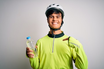 Young handsome cyclist man wearing security bike helmet drinking bottle of water with surprise face pointing finger to himself