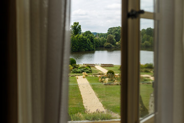 Wedding ceremony on the background of lake, top view from window. Rows of wooden chairs for guests standing on the grass in garden of France chateau. Beautiful area for open-air celebration