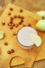Yogurt with apple and nuts on a wooden background. Daylight.