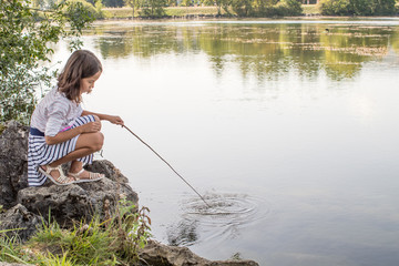 Little girl playing on the lake with branch