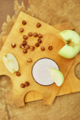 Yogurt with apple and nuts on a wooden background. Daylight.