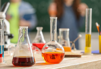 Laboratory glassware with liquids on table in classroom