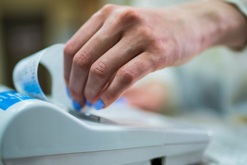The seller rips off and checks the check close-up. White cash register close-up