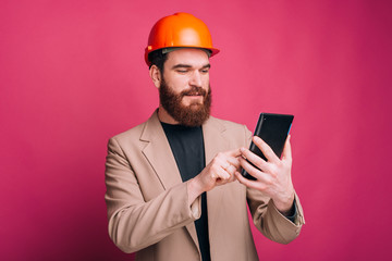 Portrait of happy architect working on tablet over pink background