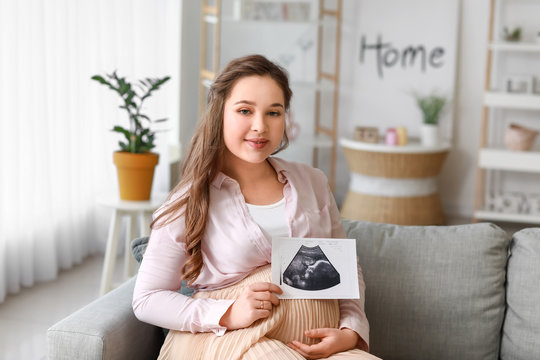 Beautiful pregnant woman with sonogram image at home