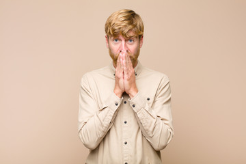 young blonde man happy and excited, surprised and amazed covering mouth with hands, giggling with a...