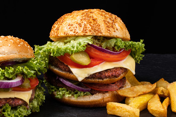 Big burger with french fries on dark background