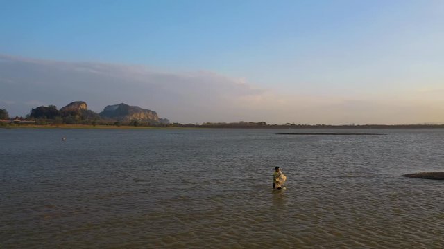 February 29th, 2020 - Perlis, Malaysia : 4k Aerial View of a man catching fish at Timah Tasoh Lake side During Beautiful Sunset with scenic Mountain view. Establishing, Drone Tracking Left
