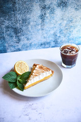 Glass of black ice coffee with slice of lemon cake - obrazy, fototapety, plakaty