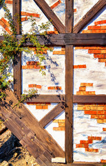 Wooden beams with red and white bricks and a climbing plant.