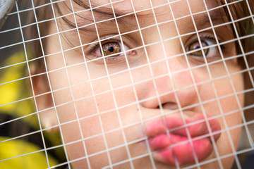 little girl looks with beautiful eyes through the net of a tennis racket