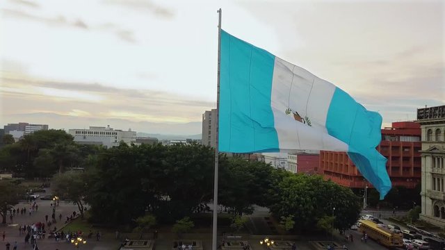 An aerial shot of the historic Parque Centenario in Zone 1 of Guatemala city with the national flag waving at golden hour. 