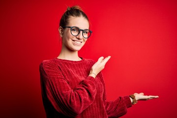 Young beautiful redhead woman wearing casual sweater over isolated red background Inviting to enter smiling natural with open hand