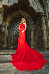 Naklejka premium A woman in a red dress stands on a background of a medieval castle