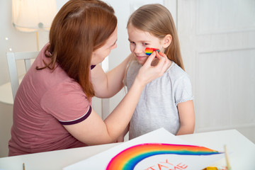 mom draws daughter of rainbow on cheek. stay home.