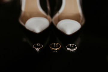 Wedding accessories on a black background.  Wedding rings, white bride's shoes.