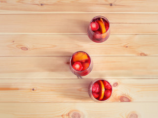 Red wine sangria with fruits in glasses on rustic wooden table.