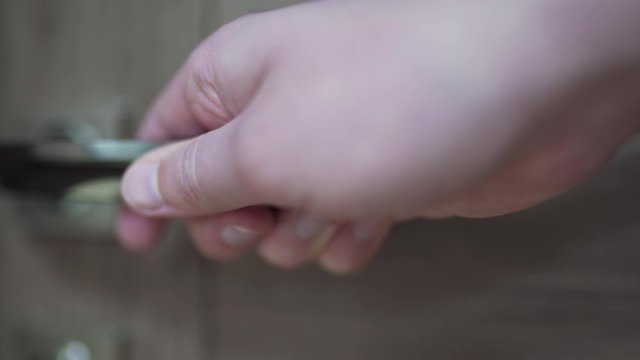 Person closes a wooden door in front of him. Hand holds door handle closeup, there is a place for your text