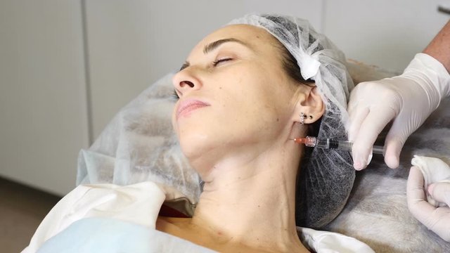 Female doctor dermatologist cosmetologist performs botulinum toxin injections for neck rejuvenation in modern beauty clinic. Full hd