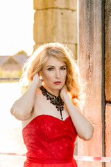 A woman in a red dress stands on a background of a medieval castle