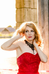 A woman in a red dress stands on a background of a medieval castle