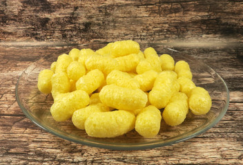 Corn sticks on a glass plate on a wooden background