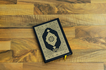 Holy Quran with Arabic calligraphy meaning of Al Quran on wood table