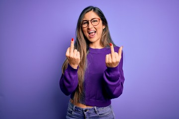 Young beautiful smart woman wearing glasses over purple isolated background Showing middle finger...