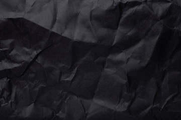 Black crumpled paper texture as background. Copy space text