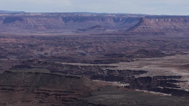 A long-lens timelapse looking across at distant canyons in Canyonlands National Park, as seen from Dead Horse Point State Park on a cloudy winter afternoon.