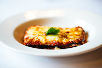 Closeup on appetizing fresh cooked italian cuisine dish  lasagna on the white plate on the white table, horizontal format