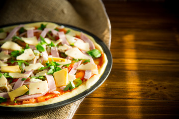 raw pizza with assorted filling in a metal form