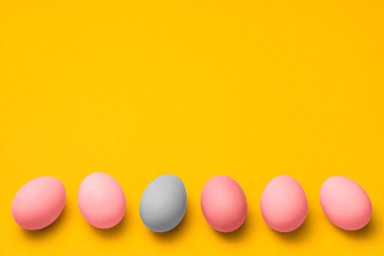 easter eggs painted in pink and blue pastel colors on a yellow background with copyspace. easter advertise minimalist concept design