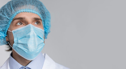 Doctor in medical mask and hair net looking at copy space