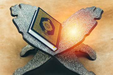 Holy Quran with Arabic calligraphy meaning of Al Quran on wood stand, islamic background
