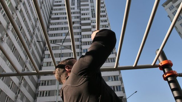 The guy, the athlete trains on the street, performs basic exercises, boxing, push-ups, pulls himself up, looks cool