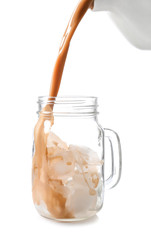 Pouring of coffee in mason jar with ice cubes on white background
