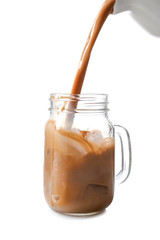 Pouring of coffee in mason jar with ice cubes on white background