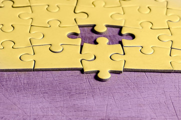 the unexpected solution.
yellow  jigsaw/puzzle with one piece at wrong position, on purple...