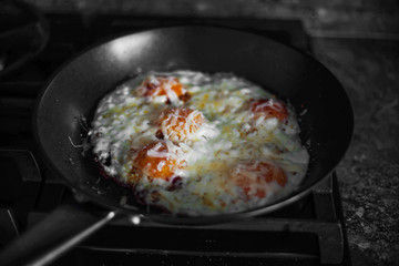Fried eggs sprinkled with cheese lie in a hot pan