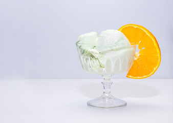 Ice cream Mint, pistachio in a glass vase and ripe orange