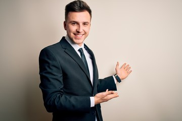 Young handsome business man wearing elegant suit and tie over isolated background Inviting to enter...