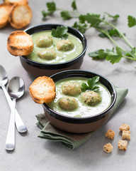 Soup-puree of greens with meatballs with croutons in a bowl on a light background