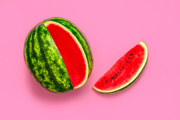Creative summer food concept. Half and pieces of ripe juicy red watermelon on bright pink...