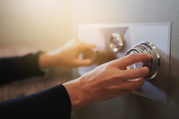 Close up of a woman hand hold and tuning on a combination safe dial lock - obrazy, fototapety, plakaty