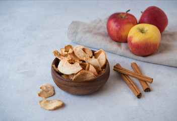 sweet homemade Apple chips baked with cinnamon in wood bowl on gray background