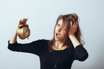 cute brunette girl slept with horror looks at an alarm clock